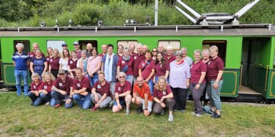 Gruppenbild im Hintergrund die Schmalspurbahn im Jura